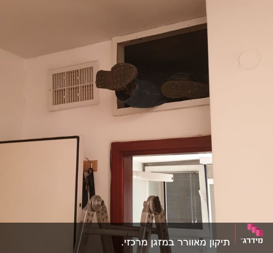 אדם עובד על מערכת מיזוג אוויר בתקרה